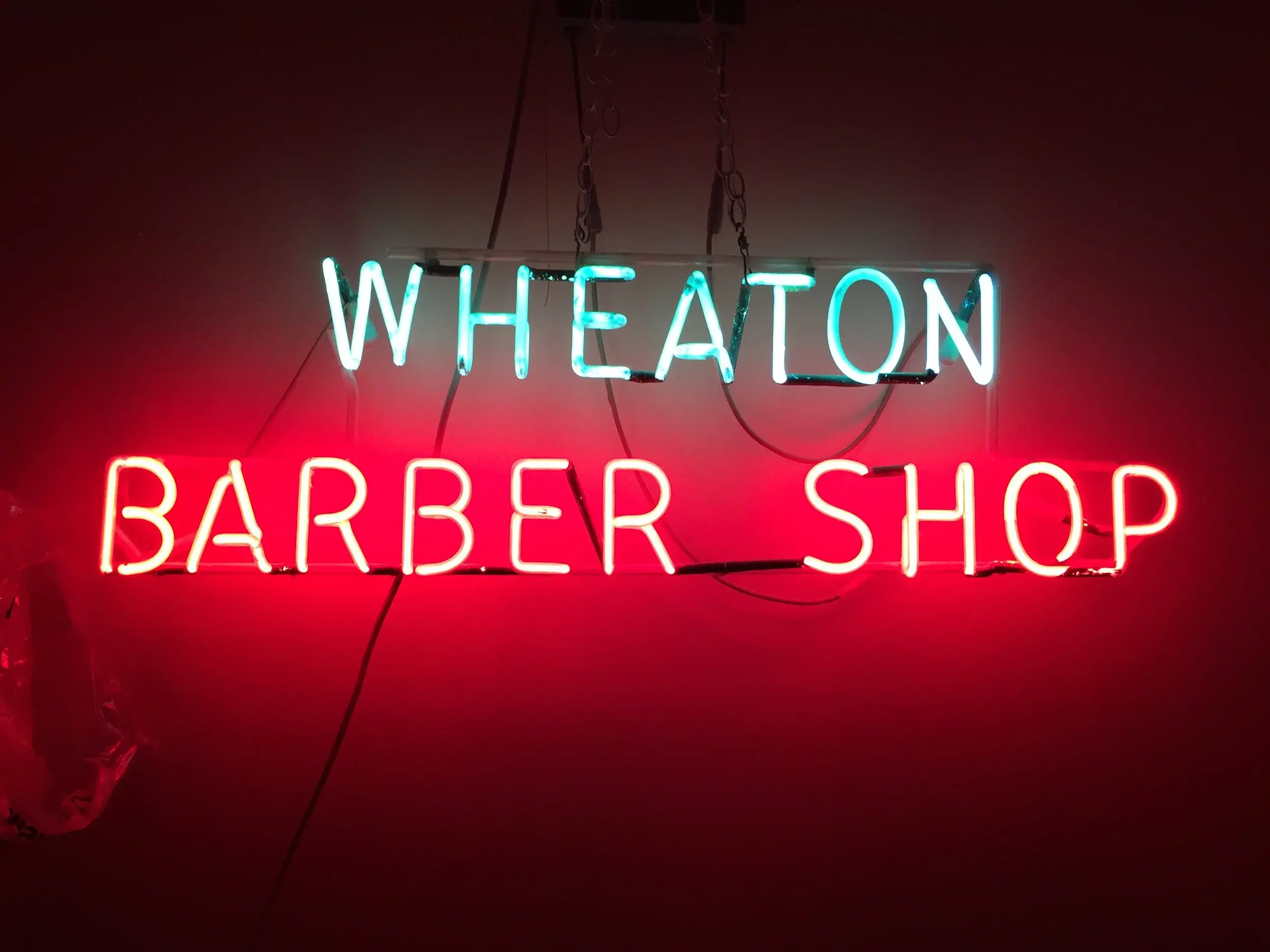 Vintage neon Wheaton Barber Shop sign glowing in red and blue