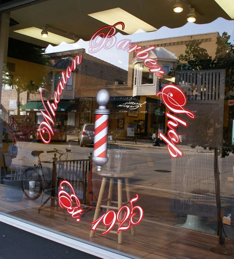 Wheaton Barber Shop Est. 1925 window display with barber pole in Winfield