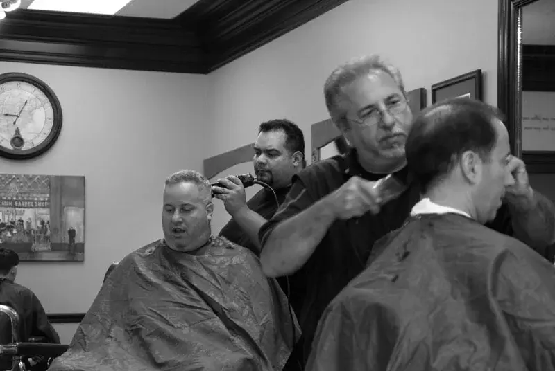 Two barbers giving haircuts side by side at Wheaton Barber Shop