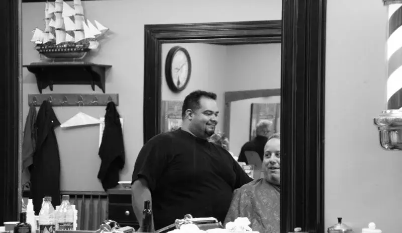 Barber and client smiling in the mirror at Wheaton Barber Shop