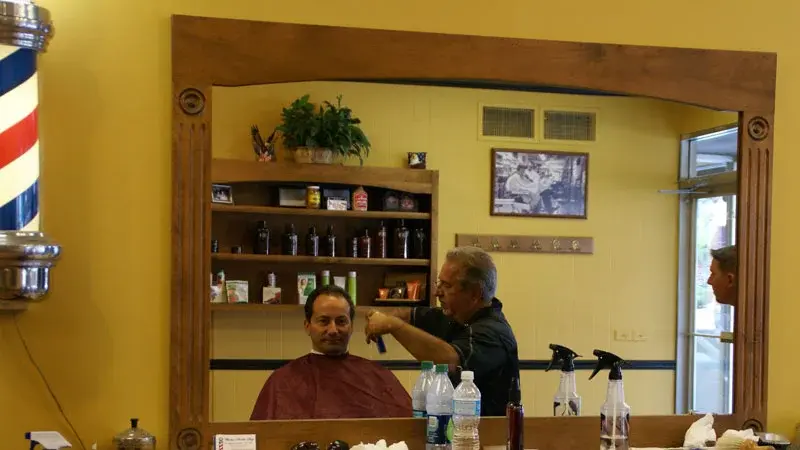 Mirror view of a haircut in progress with barber pole at Wheaton Barber Shop