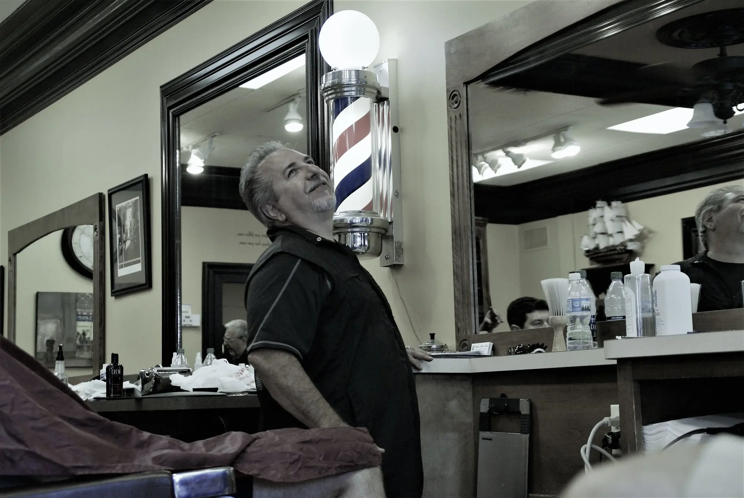 Barber laughing by the classic barber pole at Wheaton Barber Shop in Winfield