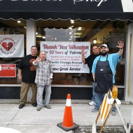 Three friends posing by the barber pole inside Wheaton Barber Shop