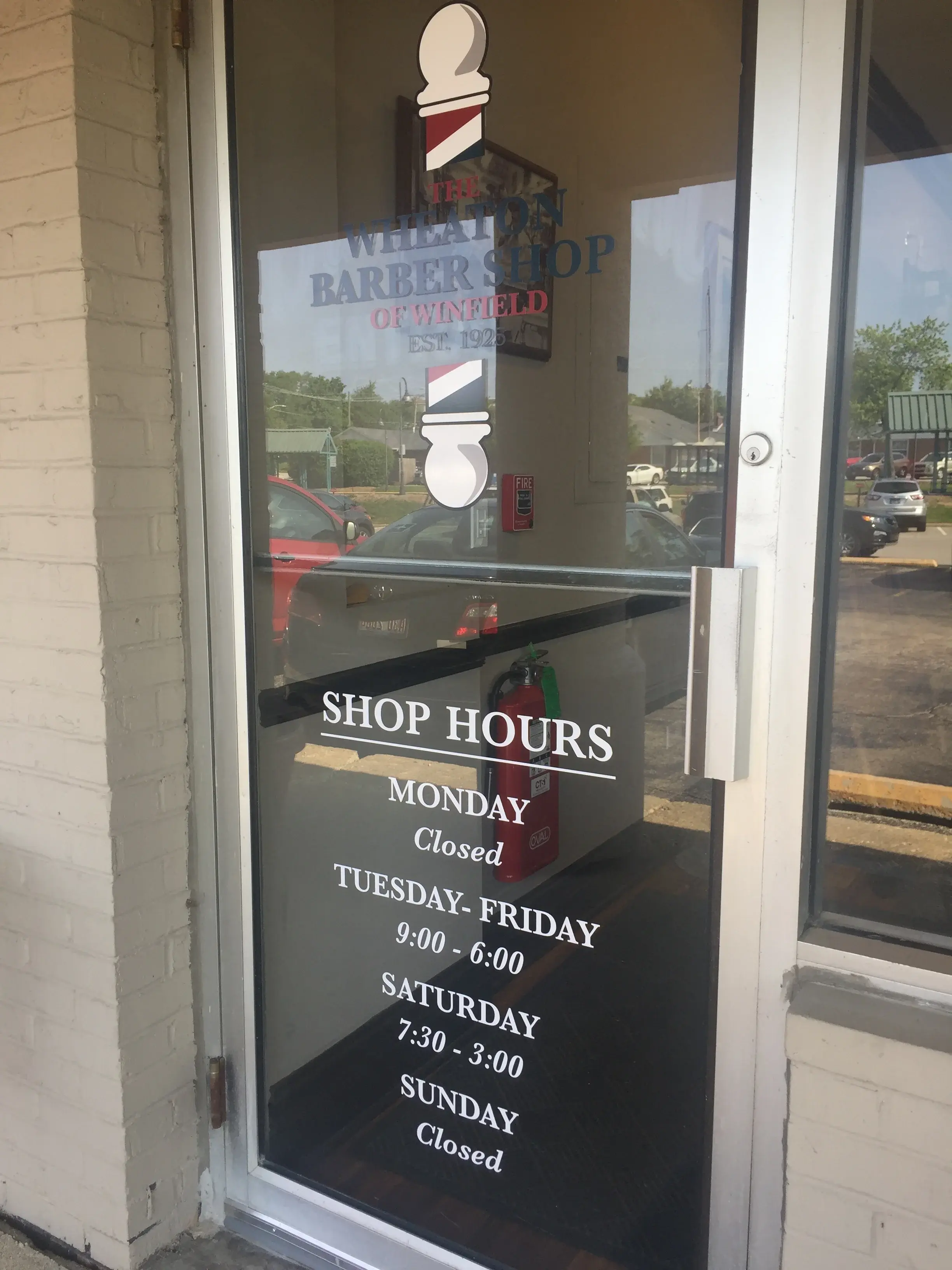 Wheaton Barber Shop front door with shop hours and barber pole logo