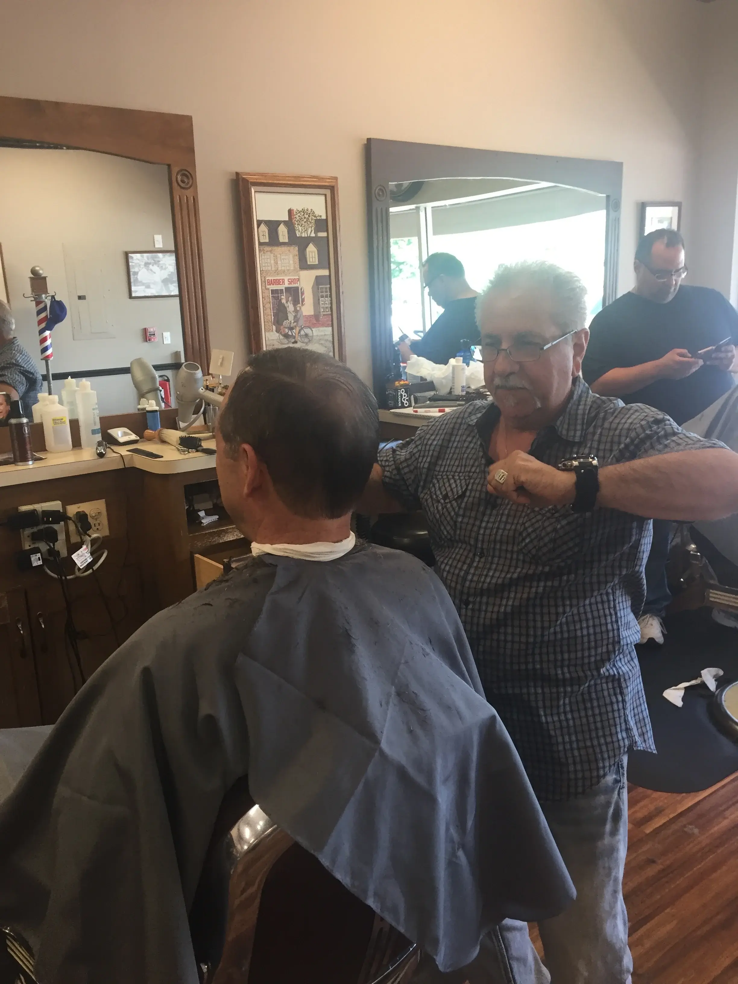 Barber giving a men's haircut at Wheaton Barber Shop in Winfield IL